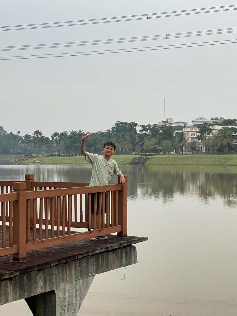 Logan waving from a lakeside dock